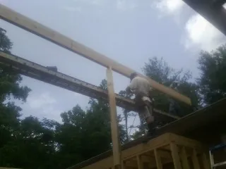 Carpenter setting a ridge beam over a new addition frame — Ice Dam Removal by Roofing Brothers in Park Falls