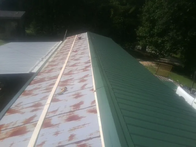 Old rusted panels beside newly installed green metal roofing — Wind Damage Roof Repair by Roofing Brothers in Park Falls