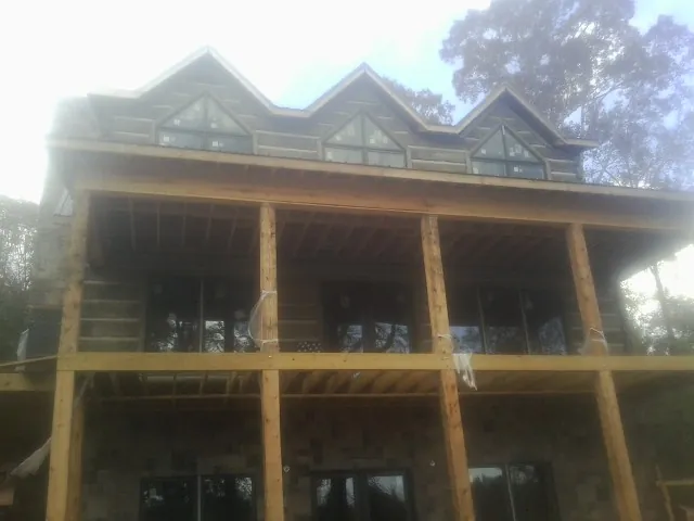 Dormers and porch framing on a large log home under construction — Roof Coating work by our crew in Park Falls