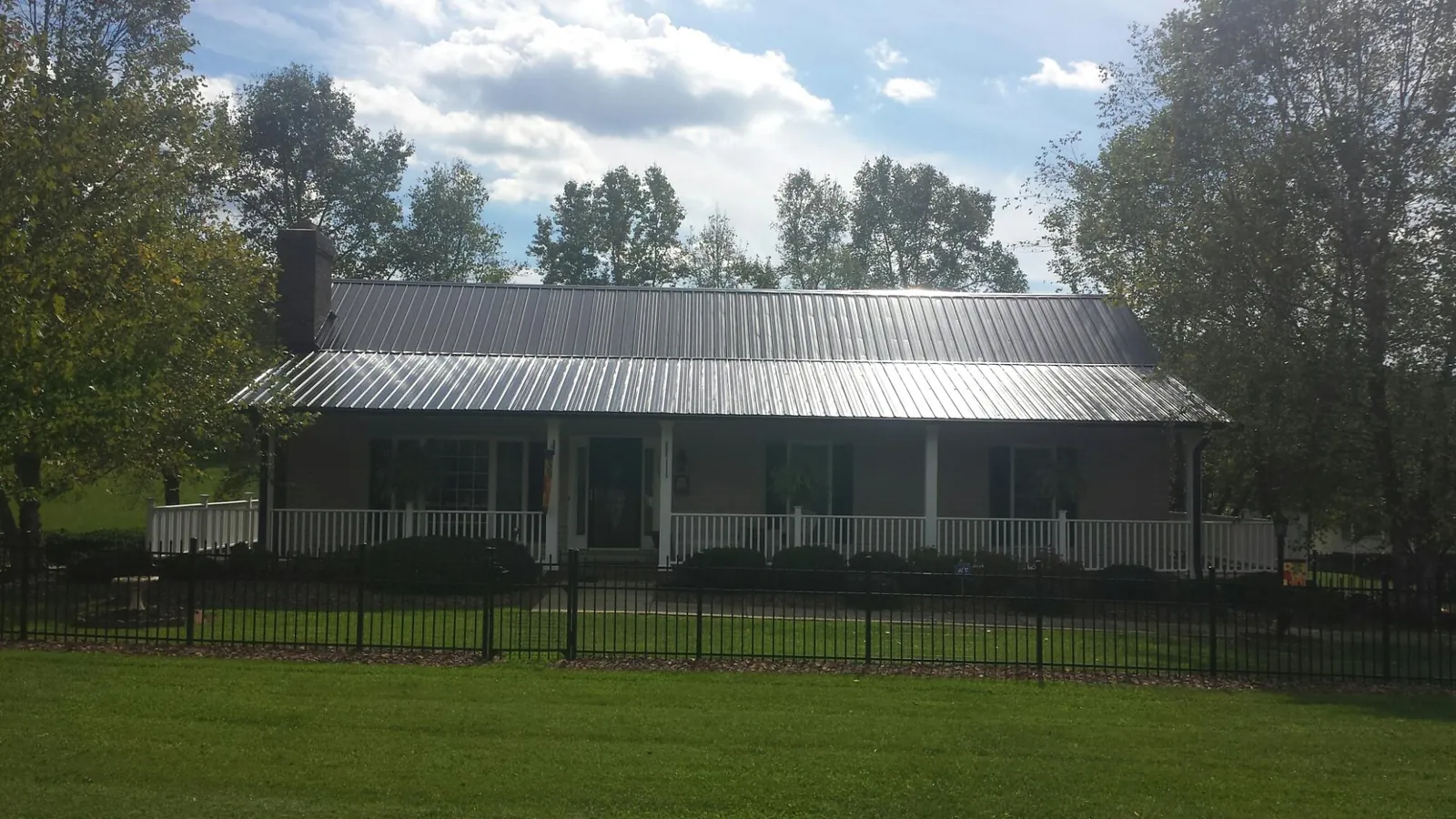 Gray metal roof on a brick ranch with a full width front porch — Gutter Guard Installation work by our crew in Park Falls
