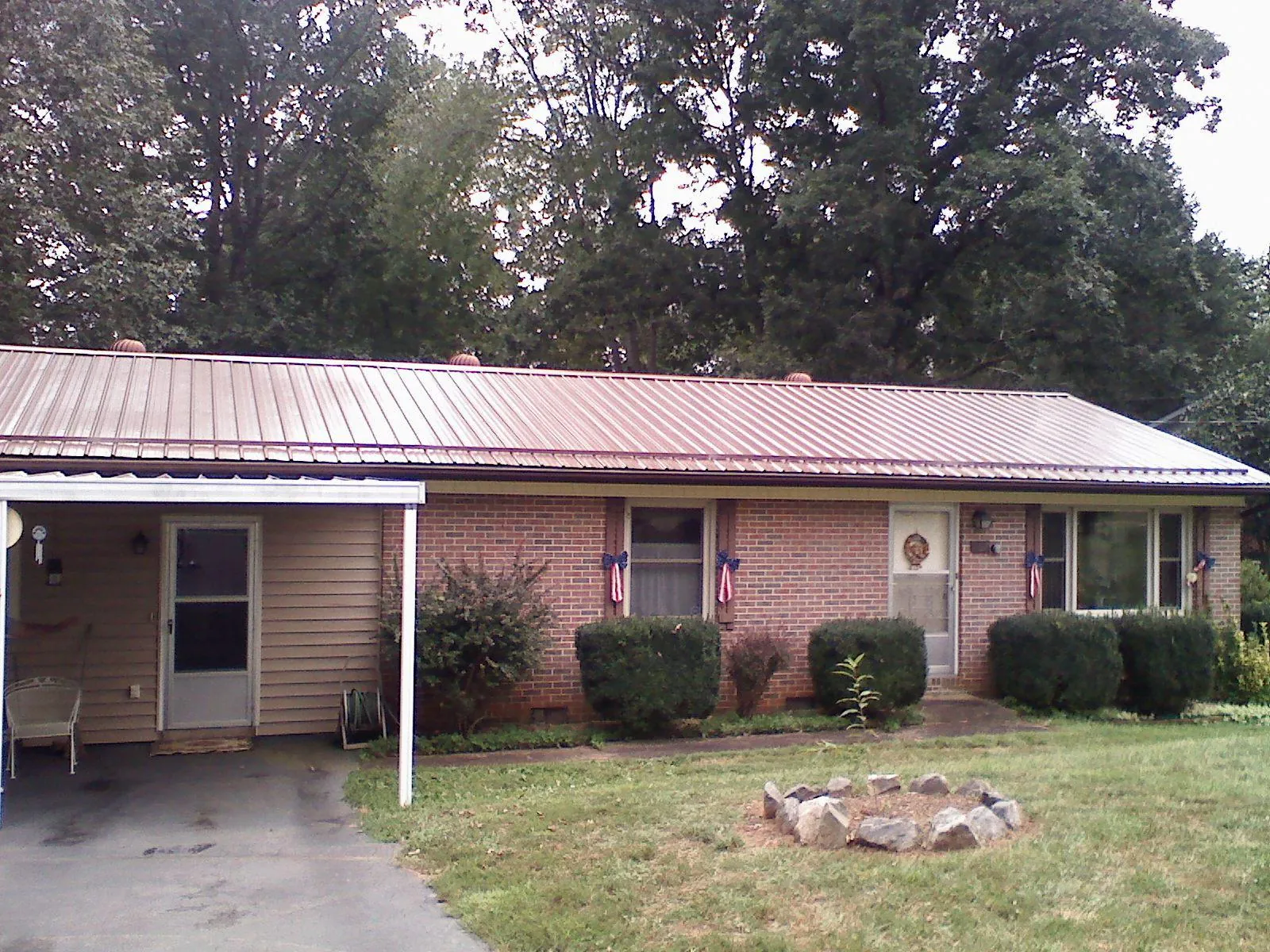 Bronze metal roof and carport on a brick ranch home — Roof Repair work by our crew in Park Falls