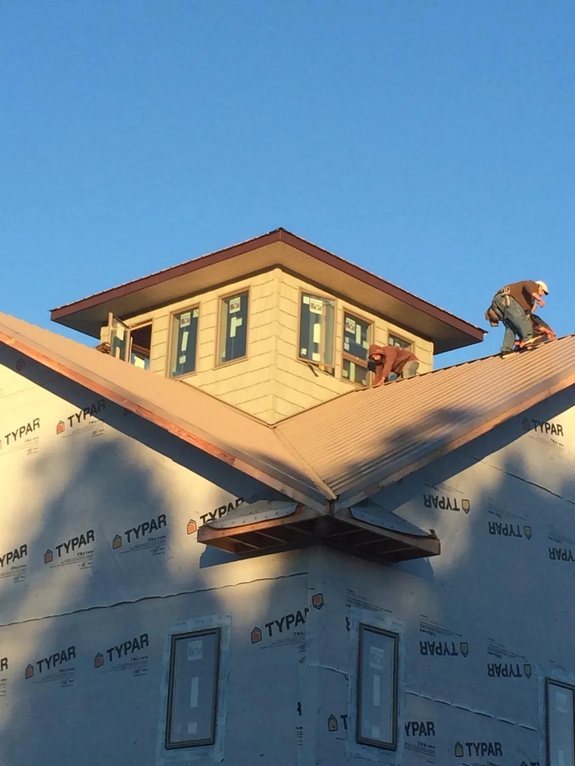 Roofers working around a rooftop cupola on a new metal roof at sunset — Roof Waterproofing in Park Falls by Roofing Brothers